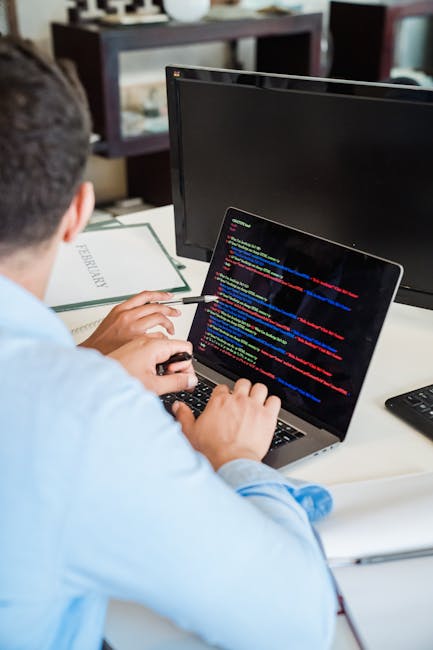 A close-up digital photograph displaying colorful computer code on a black background. The text includes various programming words and symbols in shades of blue, green, red, yellow, purple, and orange